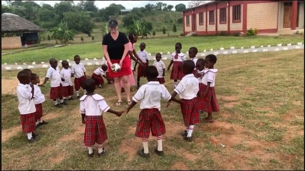 Kathy playing ball with children at Changing A Destiny Academy